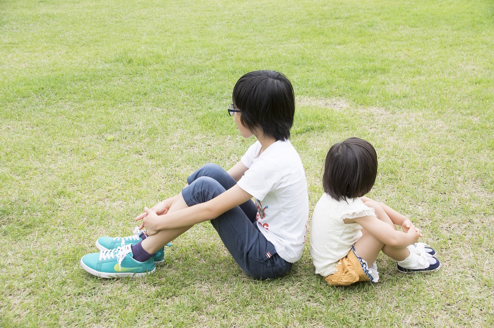 公園の芝生で座っている子供
